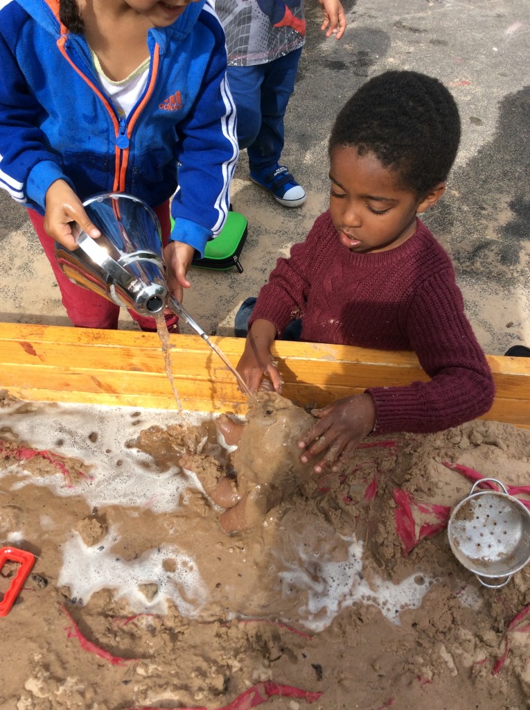 Washing dolls in the sand pit.